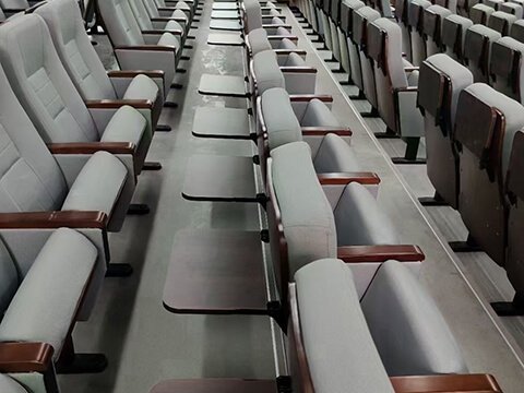 Auditorium seating with rear foldable writing tablet