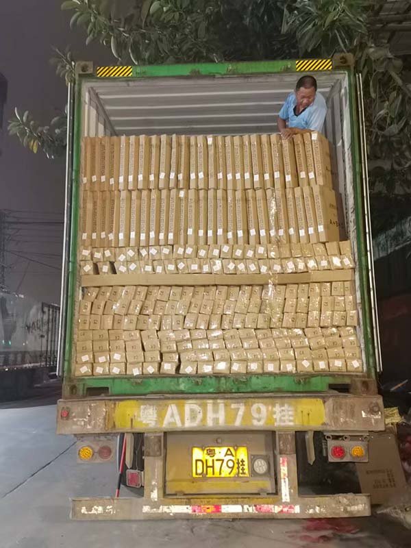 Workers loading airport benches into container at factory warehouse
