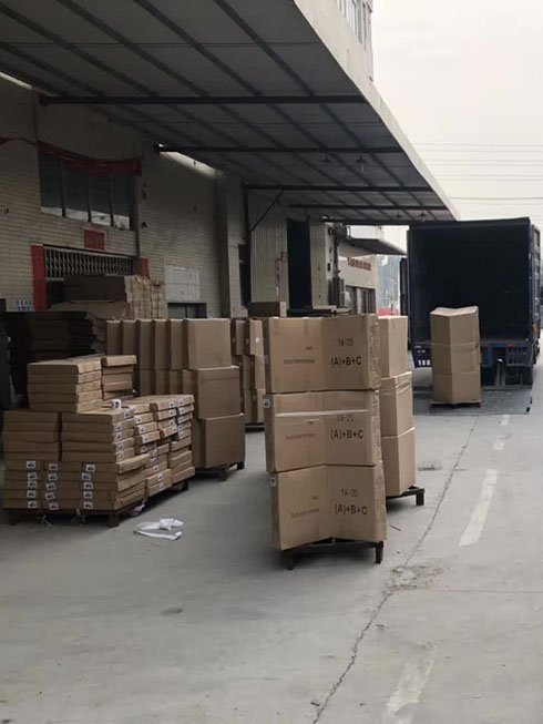 Workers loading auditorium and airport chairs into shipping container at Yeplley factory
