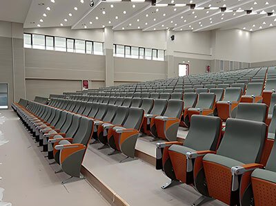 Close-up of aluminum-leg auditorium chairs in rows with writing tablet open