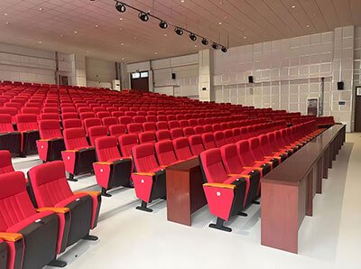 Side angle showing tiered seating layout with plastic shell chairs and front writing tablets
